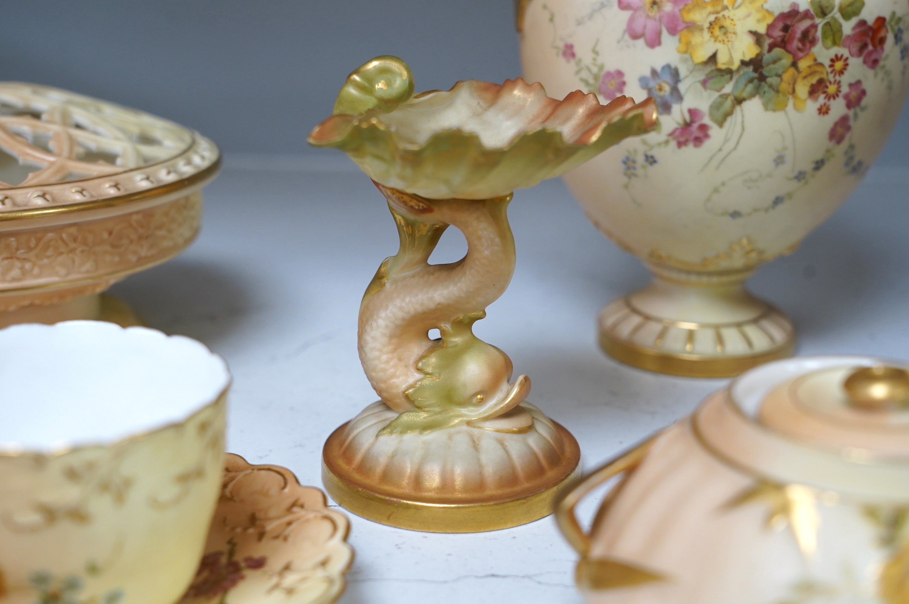 Royal Worcester blush ivory ornamental items: including a vase, two pots and covers, two dolphin stands, a cup and saucer and pierced bowl and cover (8). Condition - fair to good